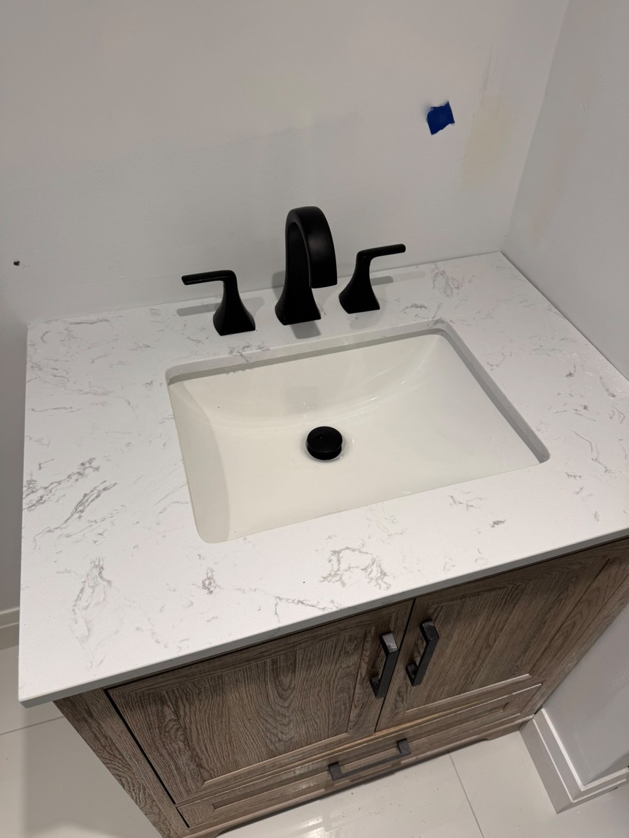 Bathroom vanity with a marble top and black faucet