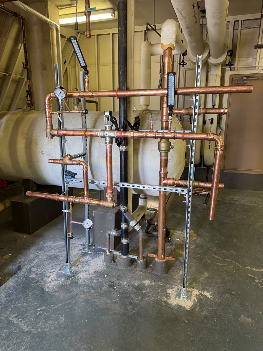 New copper piping feeding a hot water tank in a mechanical room