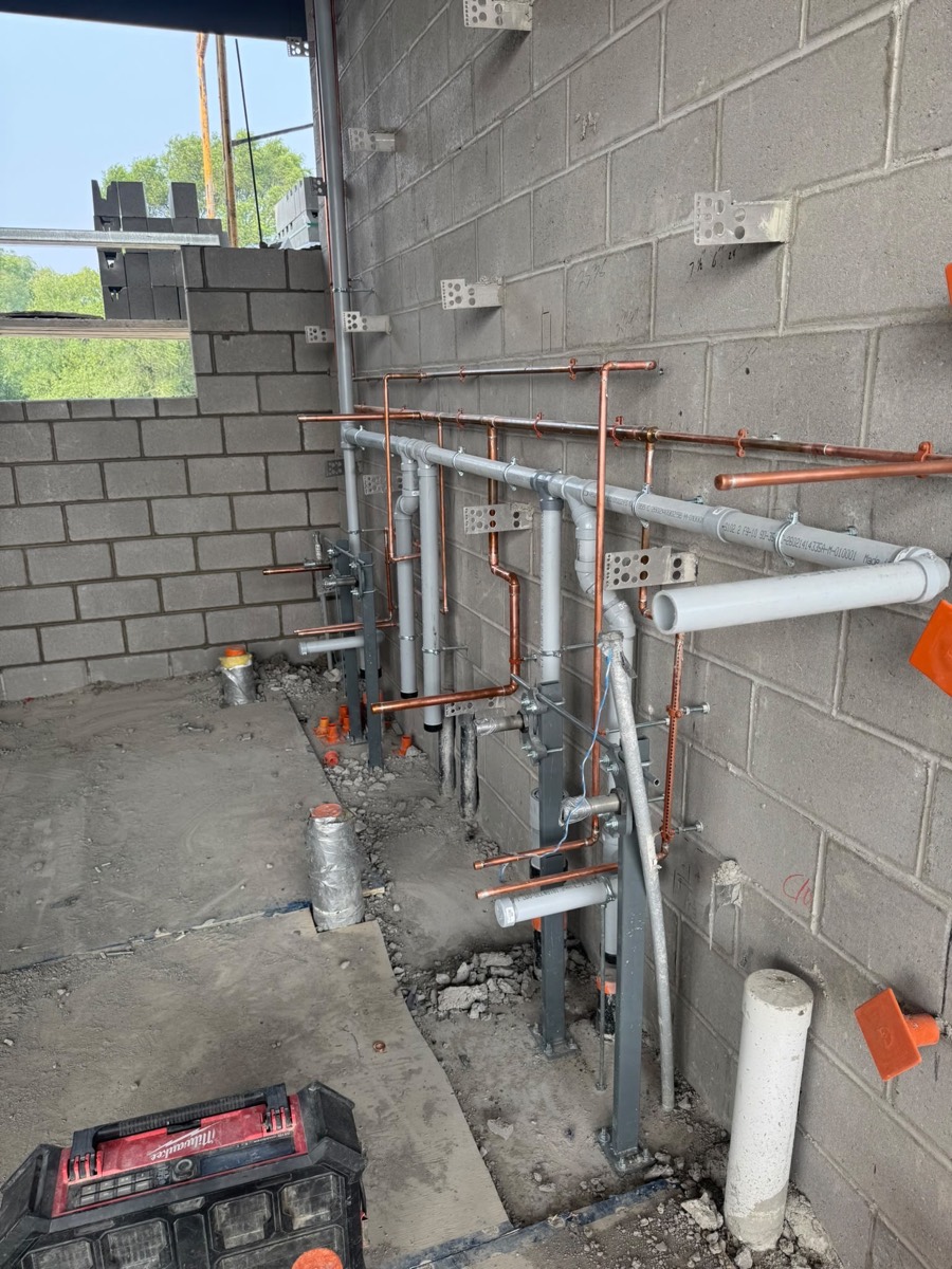 Copper and PVC rough-in along a concrete block wall