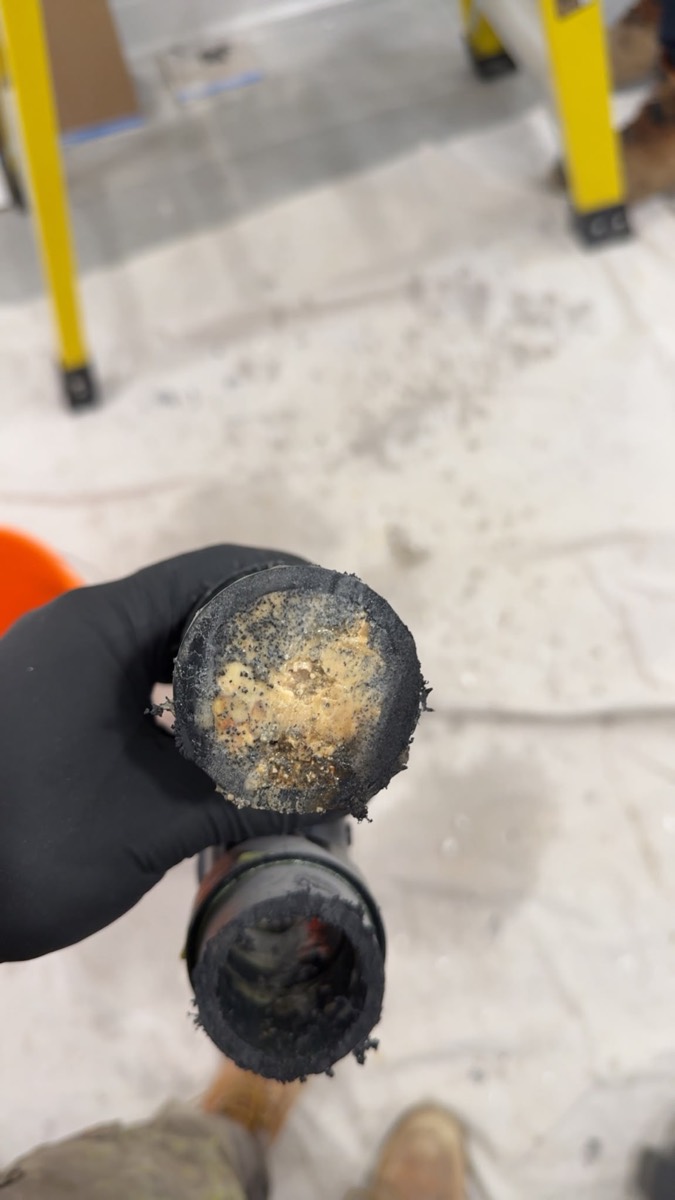 Corroded pipe section with heavy scale, held up for the camera