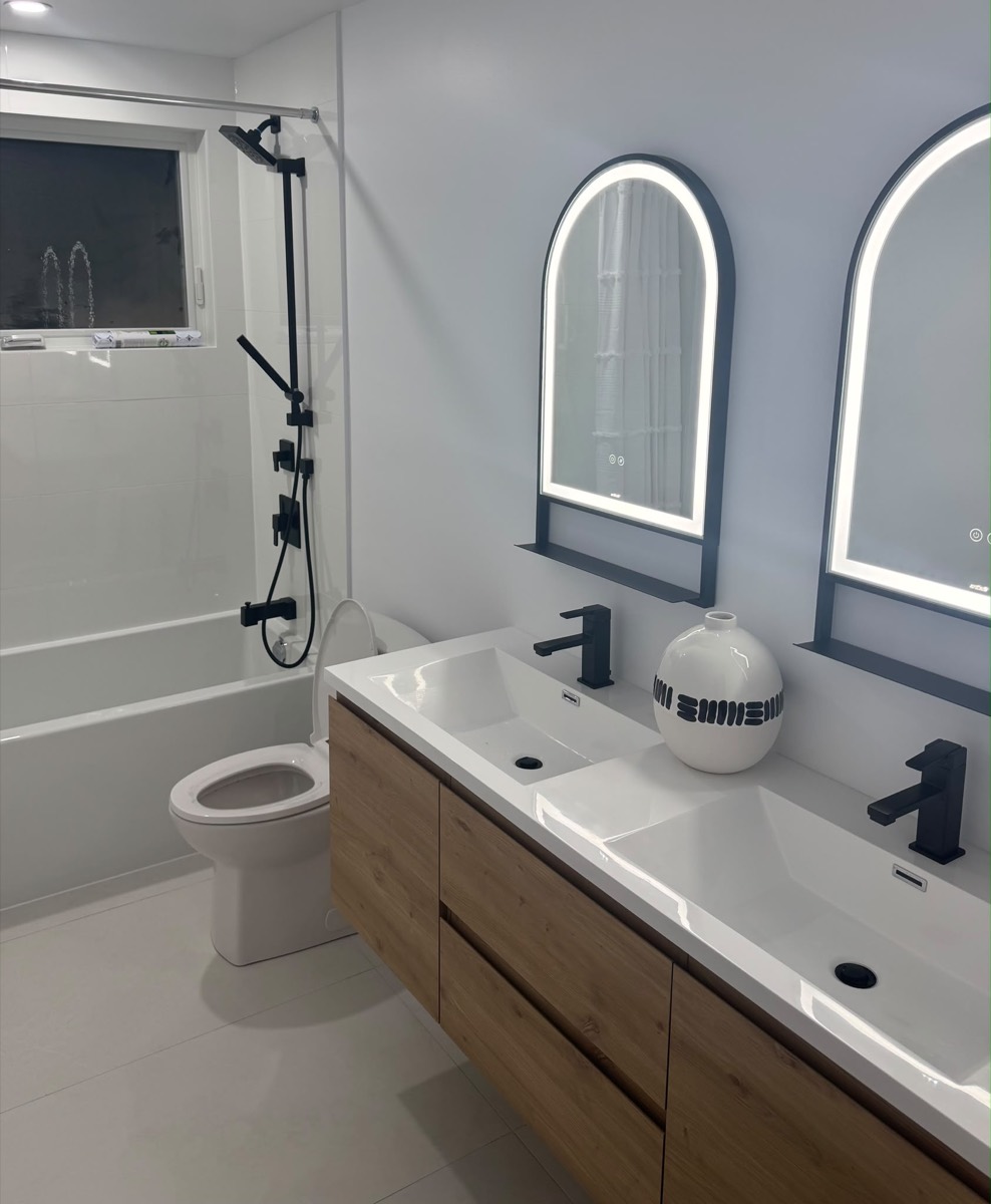 Finished bathroom with a double vanity and arched mirrors