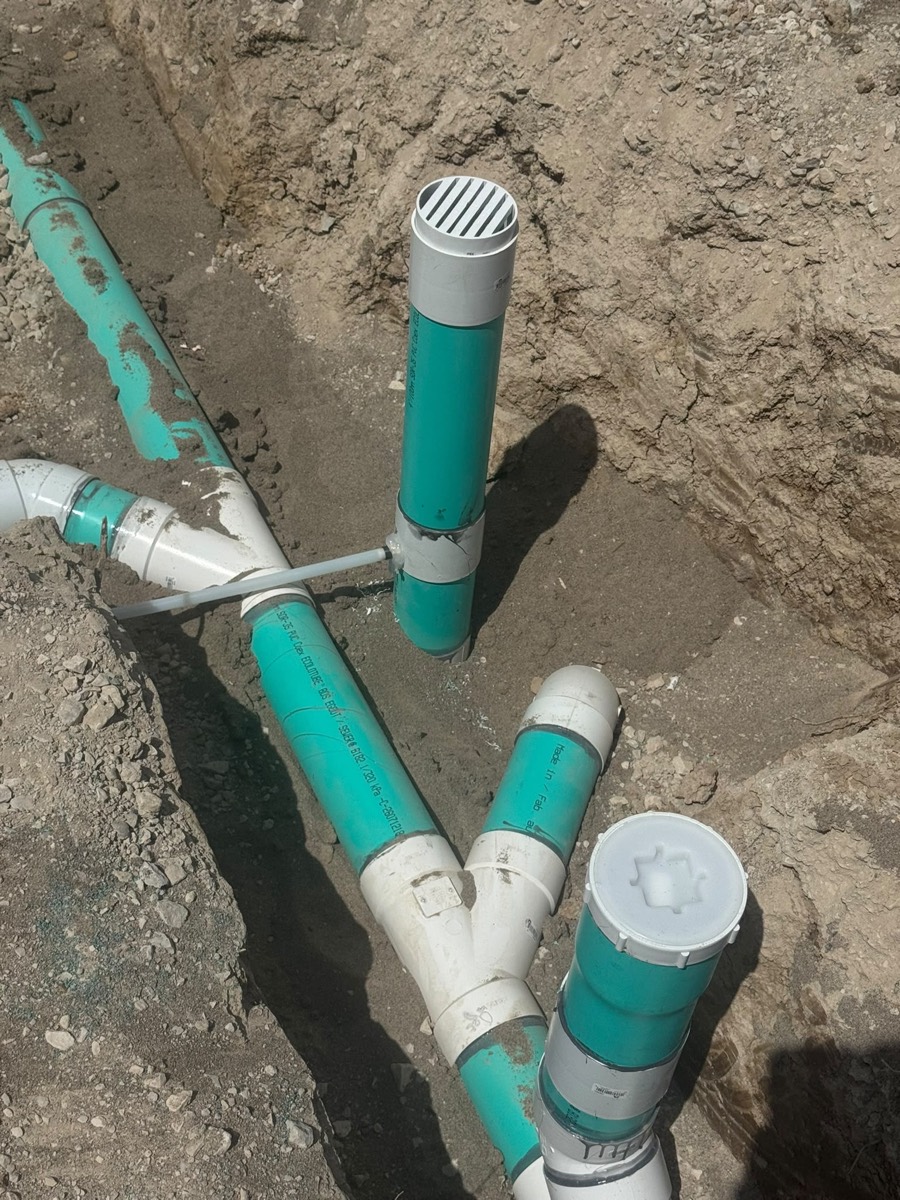 New PVC drain lines with cleanout caps in an open trench