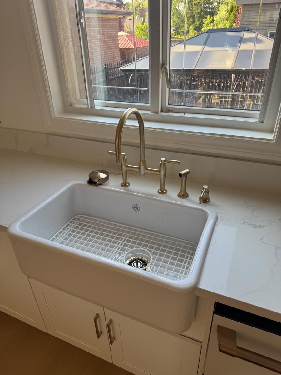 Farmhouse kitchen sink with a brass bridge faucet