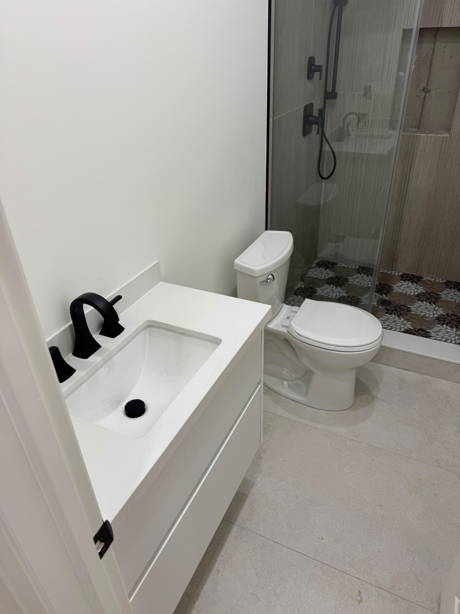 Finished bathroom with a white vanity, toilet and glass shower