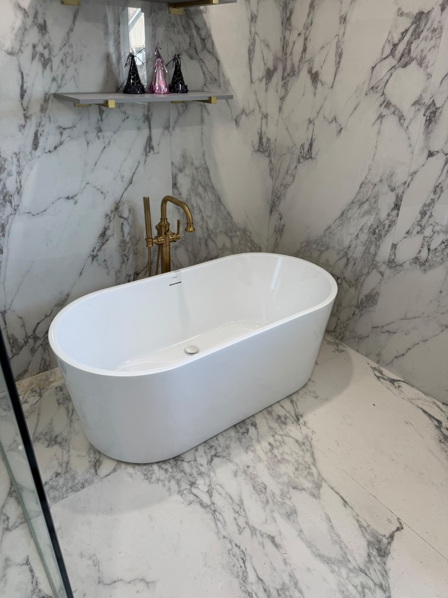Freestanding tub in a marble bathroom with a brass filler