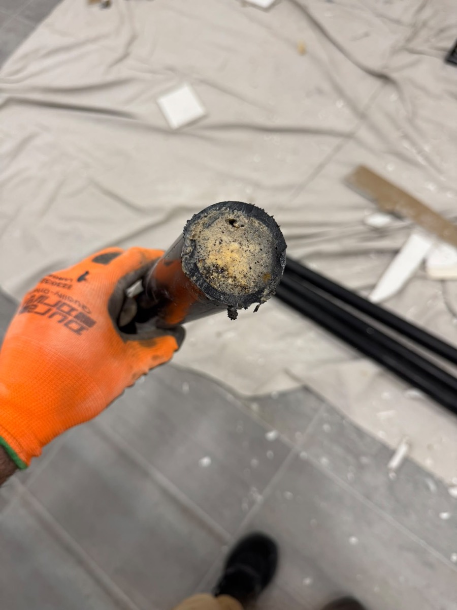 Scaled pipe section held in an orange work glove