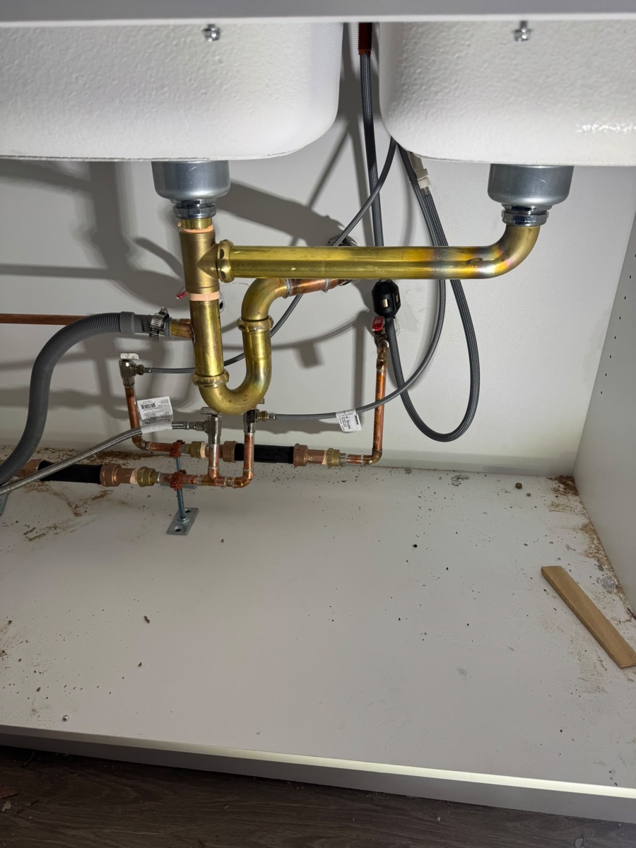 Brass drain assembly and copper supplies under a double kitchen sink